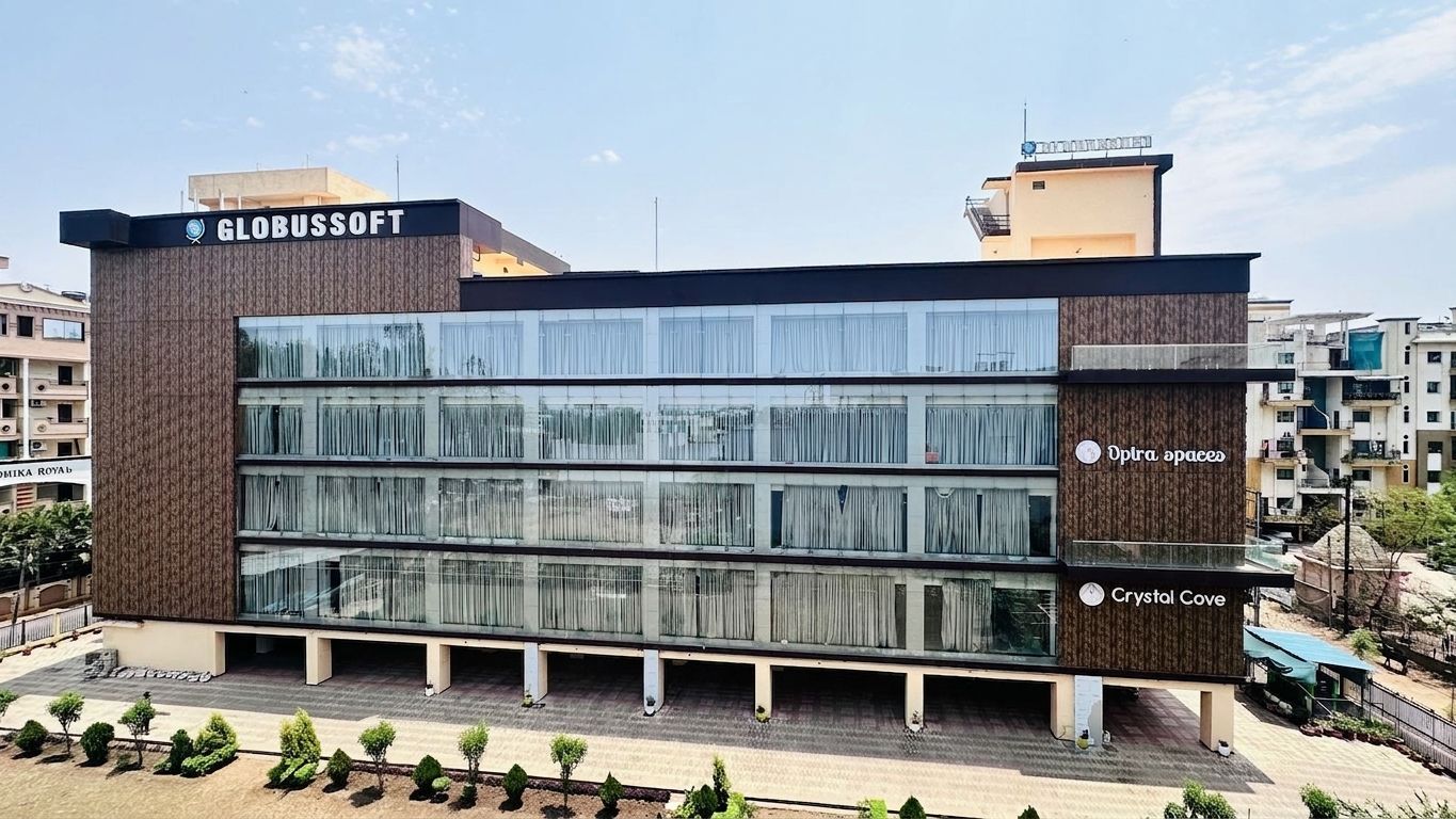 The Globussoft building: a five-storey commercial block with a
                full-height glazed frontage, company signage on the roofline, and
                covered parking at ground level.