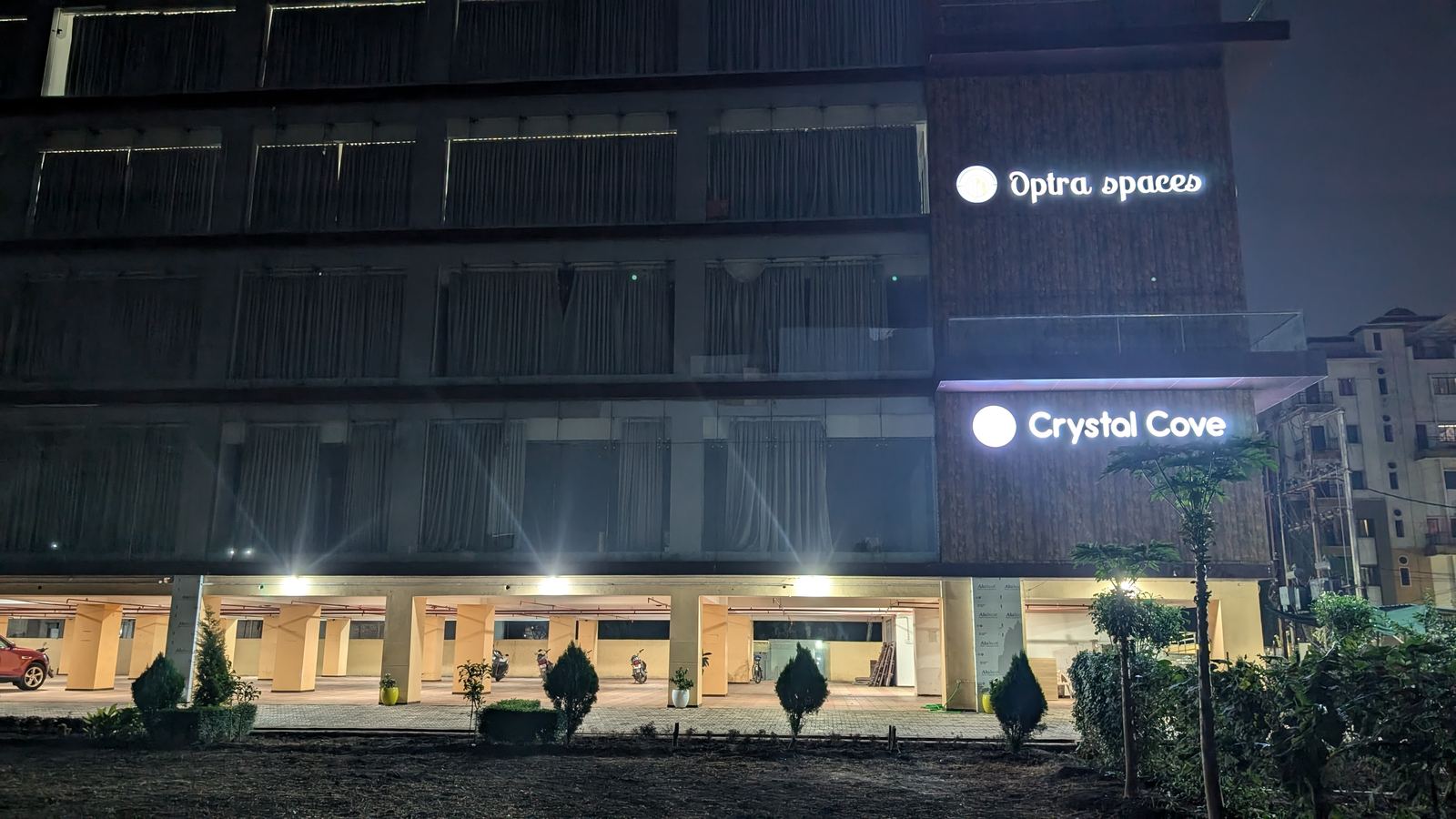 The building at night with the ground-floor parking bays lit and the
                  signage illuminated.